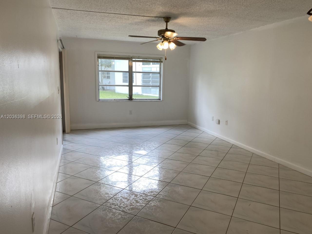 An empty room features white walls, a ceiling fan, and light-colored diagonal floor tiles — 6507 Winfield Blvd # C, Margate FL 33063, MARGATE, FL
