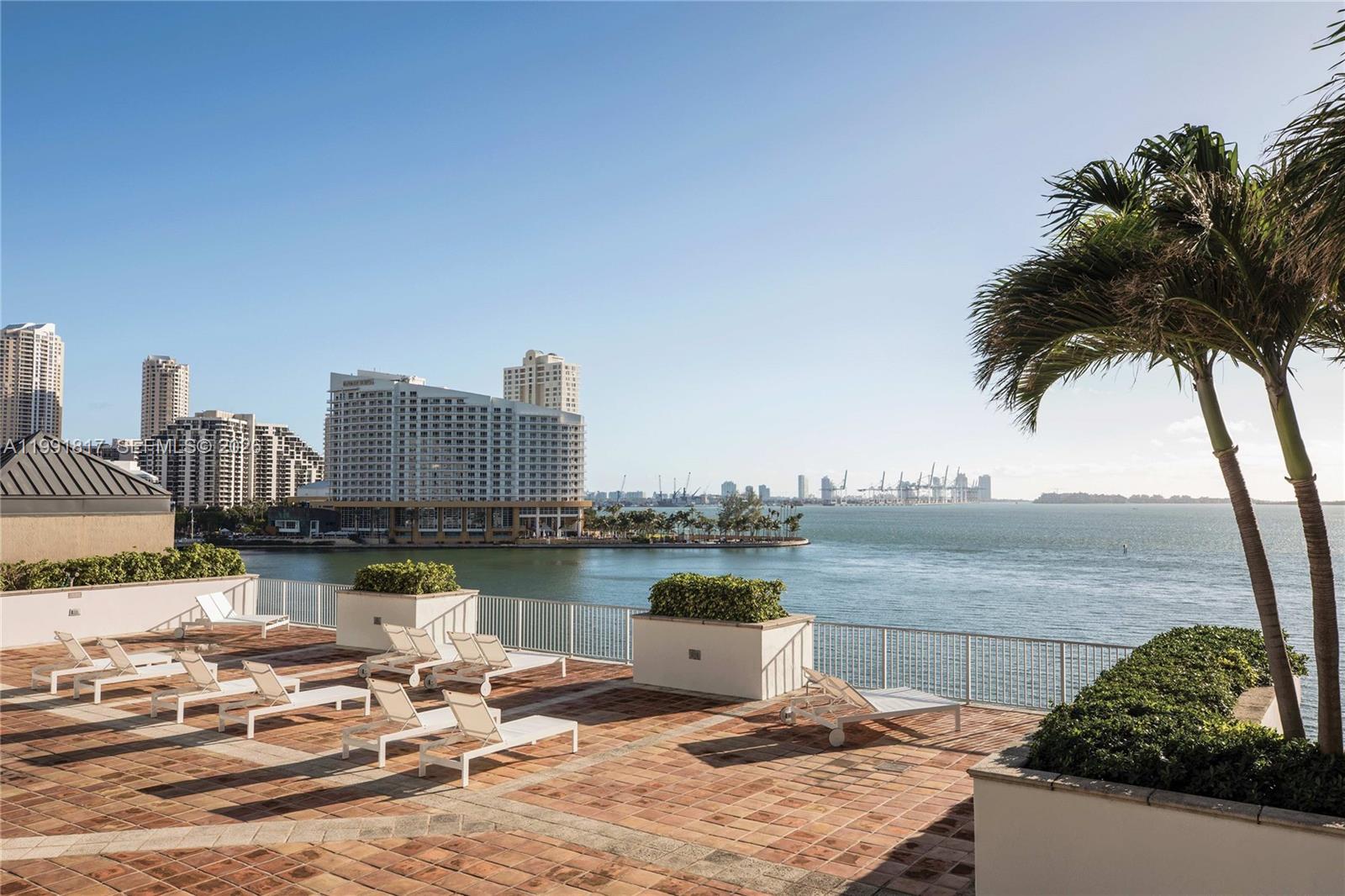 A paved outdoor terrace features lounge chairs overlooking a bay with city buildings in distance — 1111 Brickell Bay Dr # 3108, Miami FL 33131, MIAMI, FL