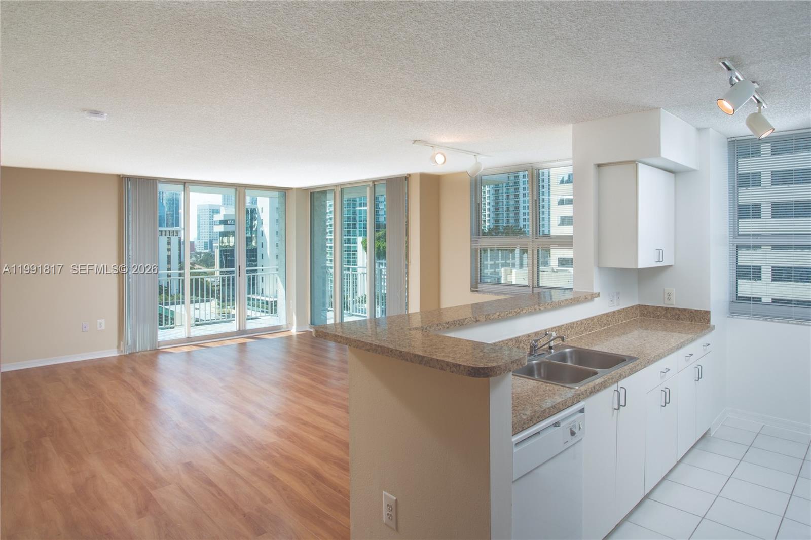 An open-concept kitchen with granite countertops overlooks a living area with floor-to-ceiling windows — 1111 Brickell Bay Dr # 3108, Miami FL 33131, MIAMI, FL