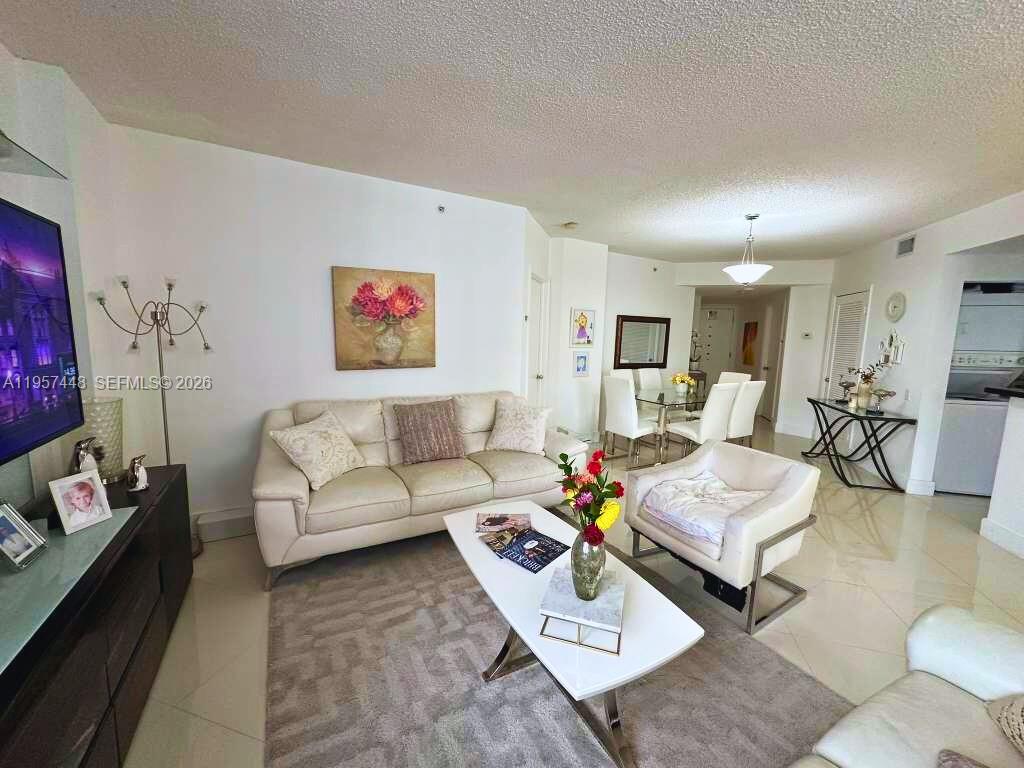 A living room features a white sofa, a modern coffee table, and tile flooring — 701 Brickell Key Blvd # 2309, Miami FL 33131, MIAMI, FL