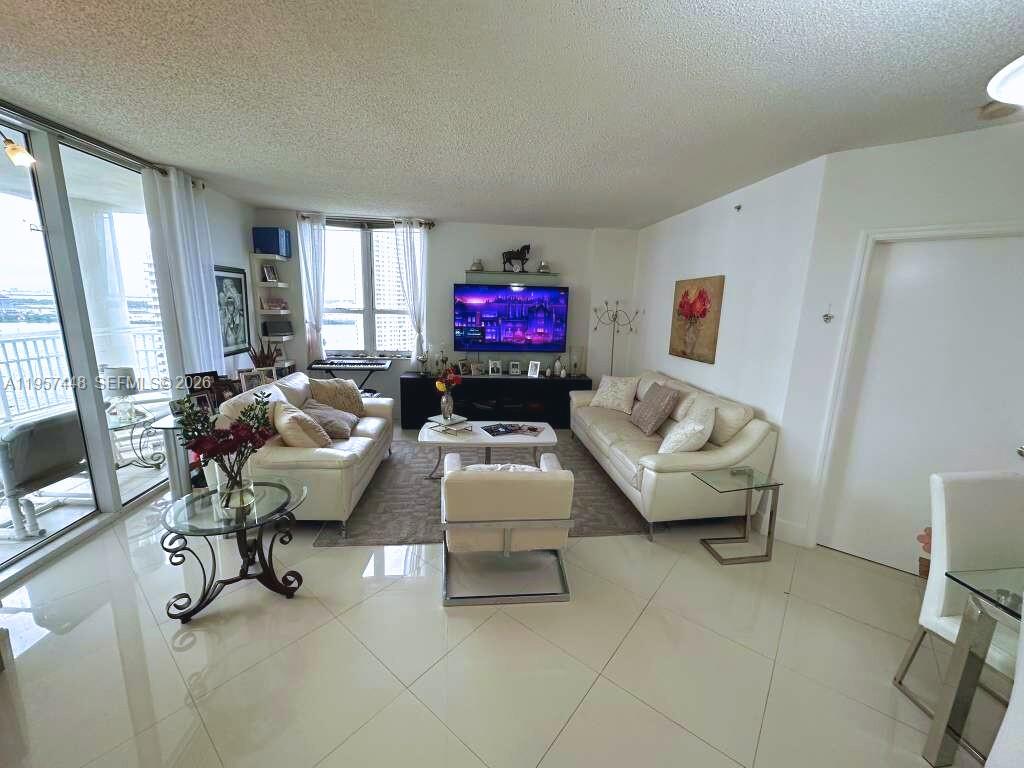 A living room features two white sofas, a central coffee table, and a wall-mounted television — 701 Brickell Key Blvd # 2309, Miami FL 33131, MIAMI, FL