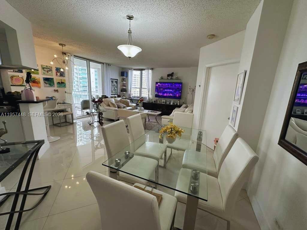 A dining area with a glass table and white chairs opens into a bright living room — 701 Brickell Key Blvd # 2309, Miami FL 33131, MIAMI, FL