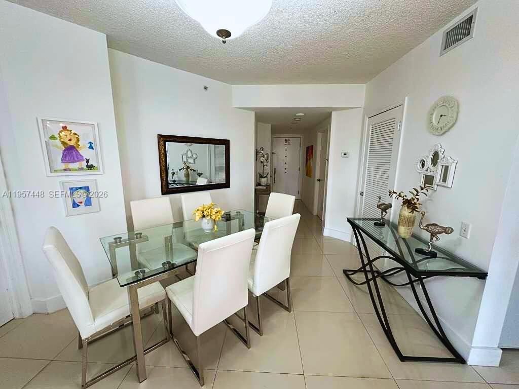 A dining room features a glass table with white chairs, tile floors, and a console table — 701 Brickell Key Blvd # 2309, Miami FL 33131, MIAMI, FL