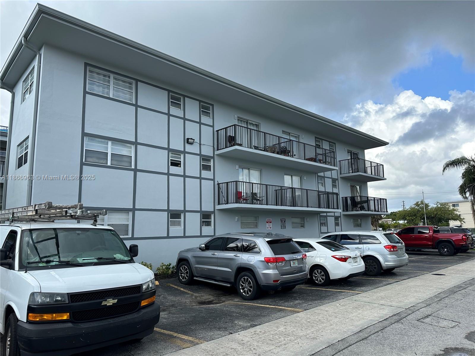 A three-story apartment building with balconies and a parking lot in front — 1100 NE 1 # 111, Hallandale Beach FL 33009, HALLANDALE BEACH, FL