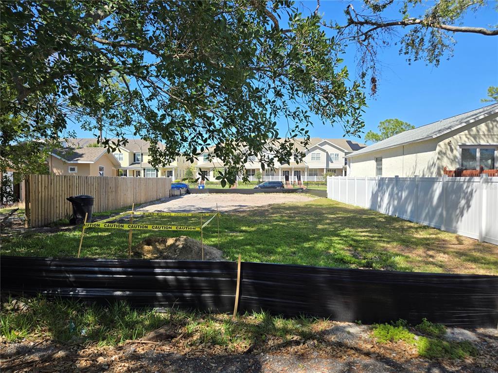 A vacant residential lot is enclosed by wooden and white vinyl fences under a tree — 134 49TH AVENUE N, ST PETERSBURG, FL