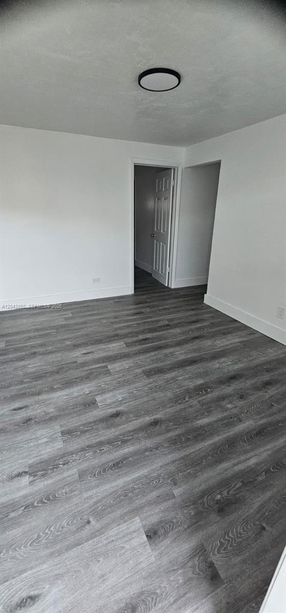 An empty room features white walls, a dark ceiling light fixture, and gray wood-look flooring — WEST PARK, FL