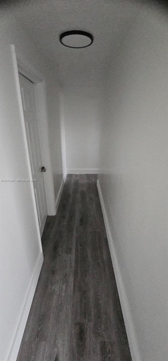 A narrow hallway features white walls, a single door, and dark wood-look flooring — WEST PARK, FL