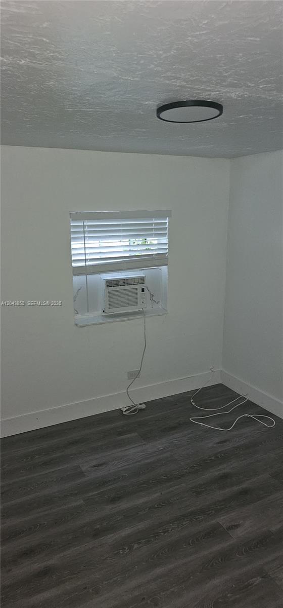 A room with gray wood-look flooring, white walls, a window air conditioner, and a ceiling light — WEST PARK, FL