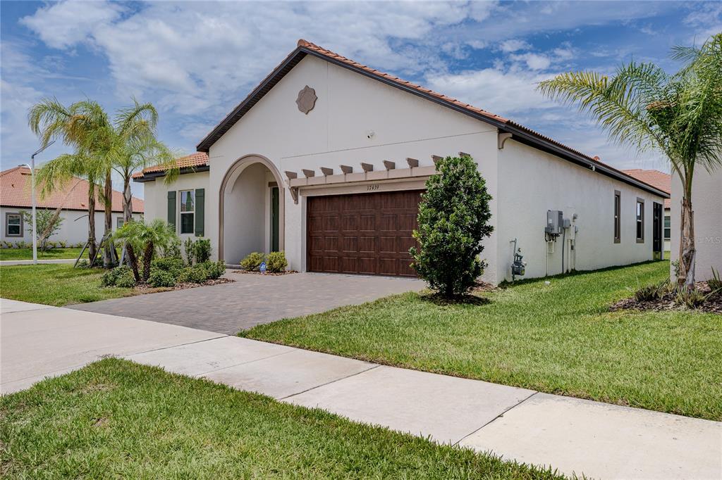 A single-story house with a stucco exterior, a brown garage door, and a tiled roof — 17439 HOLLY WELL AVENUE, WIMAUMA, FL