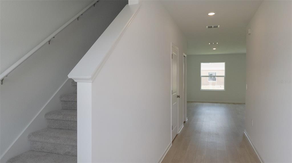 A hallway features light wood-look flooring, a carpeted staircase with a railing, and recessed lighting — 6433 DOMIZIO DRIVE, WINTER HAVEN, FL