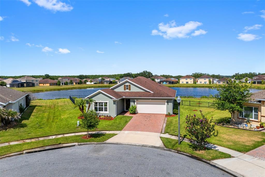 A single-story house with a two-car garage sits on a lot overlooking a lake — 4851 PEARL LAKE COURT, KISSIMMEE, FL
