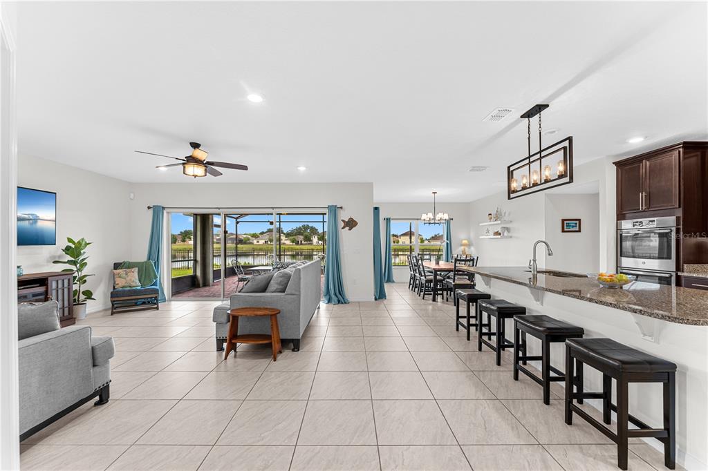 An open-concept living and dining area features tile floors, a kitchen island, and sliding glass doors — 4851 PEARL LAKE COURT, KISSIMMEE, FL