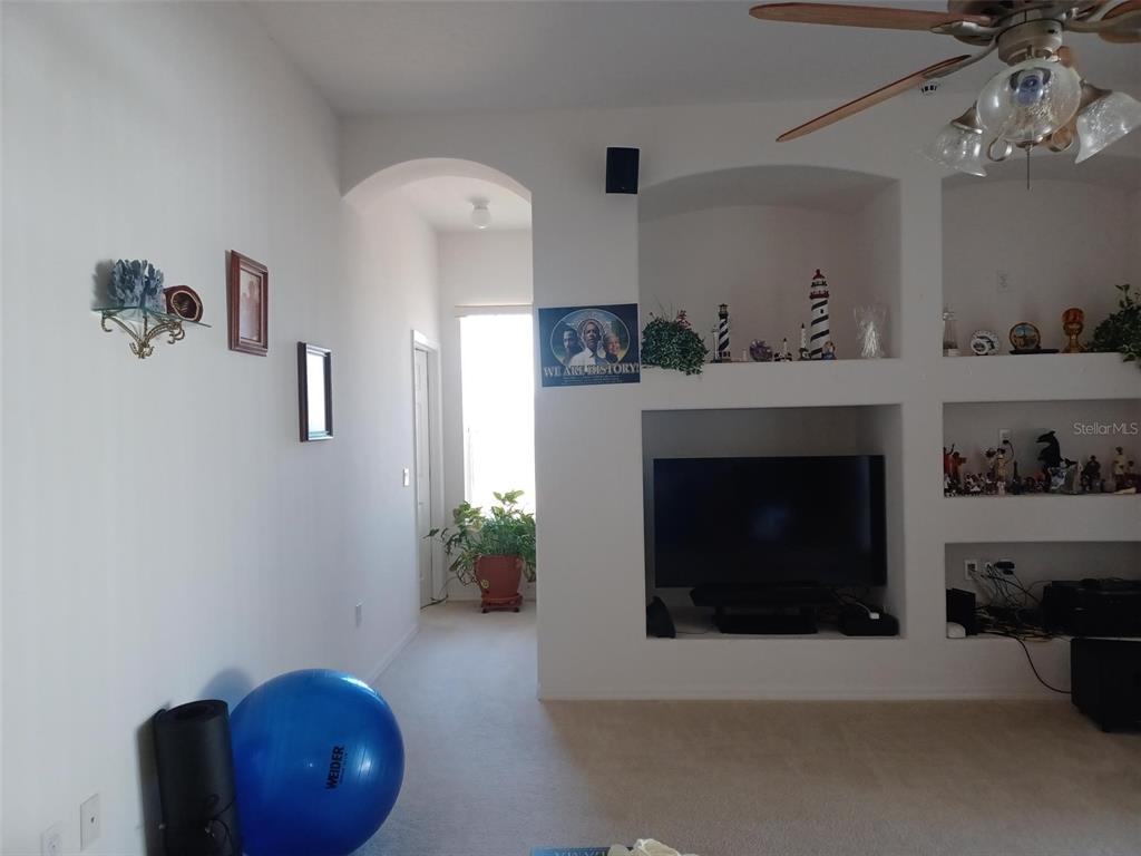 A living room features a built-in media niche, an arched hallway, and a blue exercise ball — 3513 BEAU CHENE DRIVE, KISSIMMEE, FL