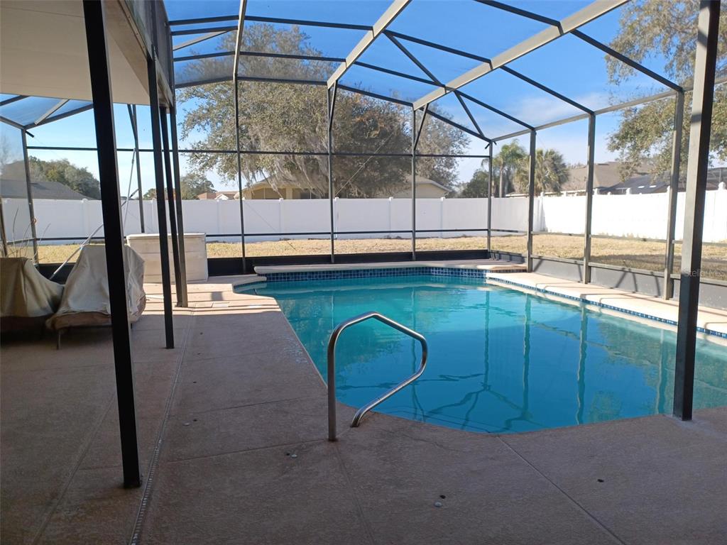 A swimming pool is enclosed by a screened lanai with a concrete deck and white fencing — 3513 BEAU CHENE DRIVE, KISSIMMEE, FL