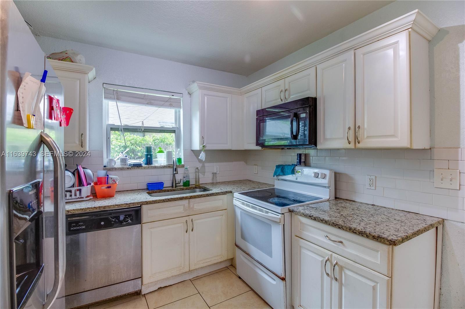 A kitchen features white cabinets, granite countertops, a stainless steel dishwasher, and white appliances — 322 N C Street, FL 33460, FL