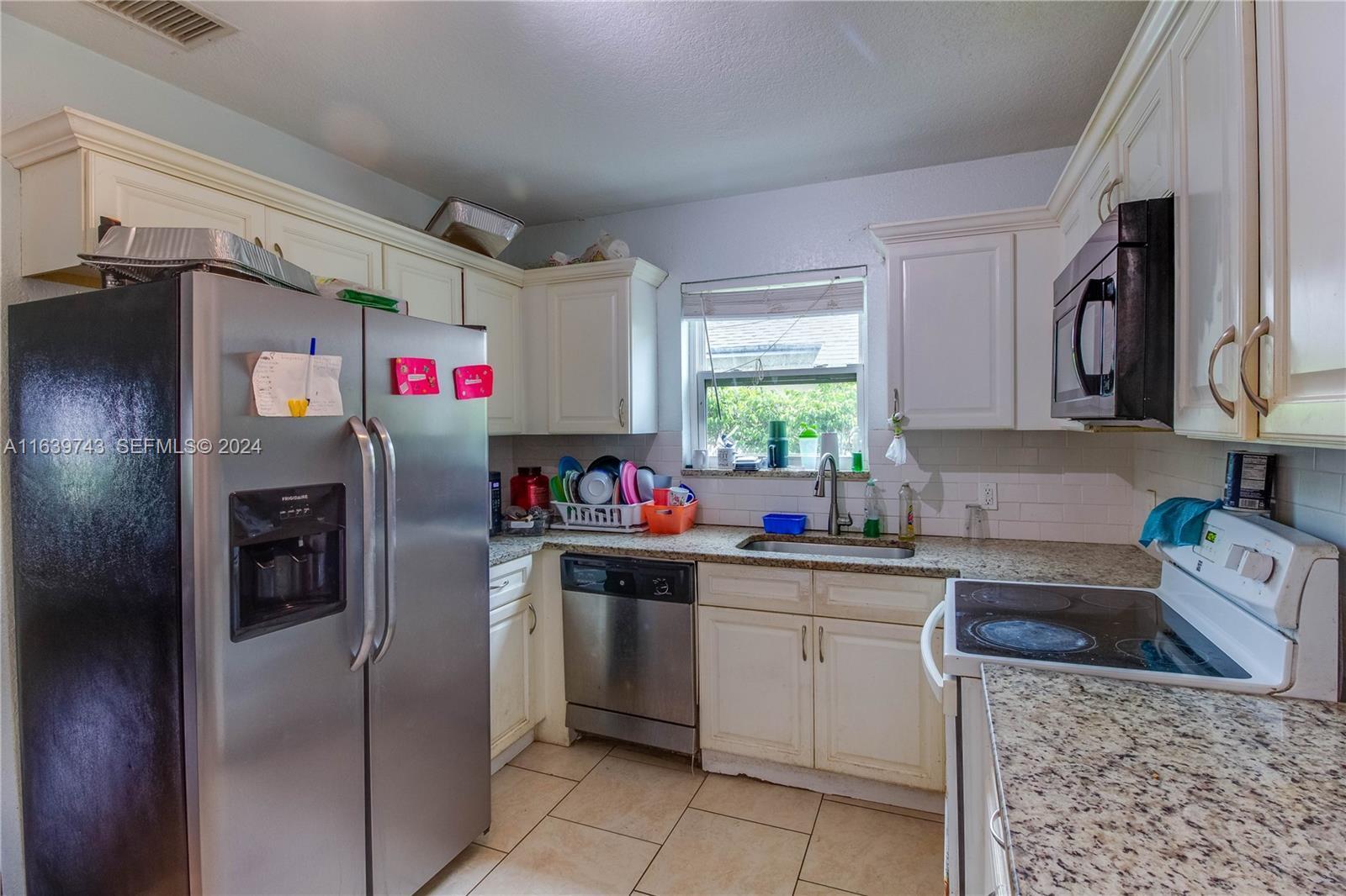A kitchen features white cabinets, granite countertops, stainless steel appliances, and a window above the sink — 322 N C Street, FL 33460, FL