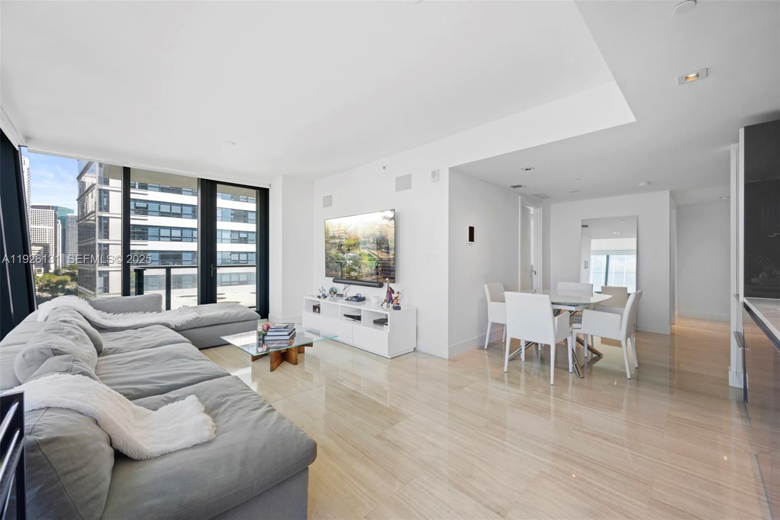 A modern living and dining area features light tile floors, a gray sectional, and balcony views — 1451 Brickell Ave # 1106, Miami FL 33131, MIAMI, FL