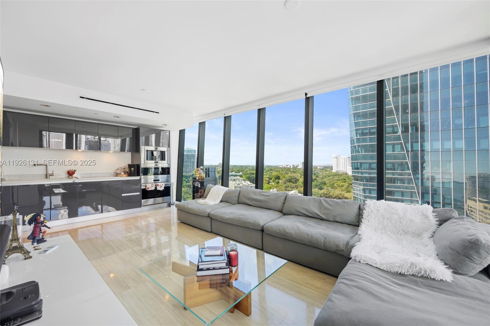 A modern living room with a gray sectional sofa, glass coffee table, and floor-to-ceiling windows — 1451 Brickell Ave # 1106, Miami FL 33131, MIAMI, FL