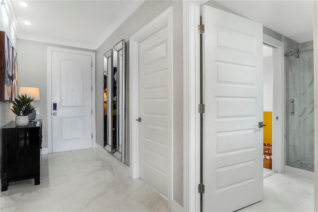 A hallway with white doors, marble-style flooring, a black console table, and a glass shower — 16300 COUNTY ROAD 455 UNIT 401, MONTVERDE, FL