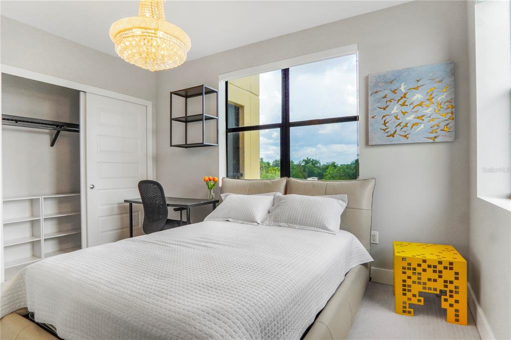 A bedroom features a bed, a desk, a closet, and a bright yellow side table — 16300 COUNTY ROAD 455 UNIT 401, MONTVERDE, FL