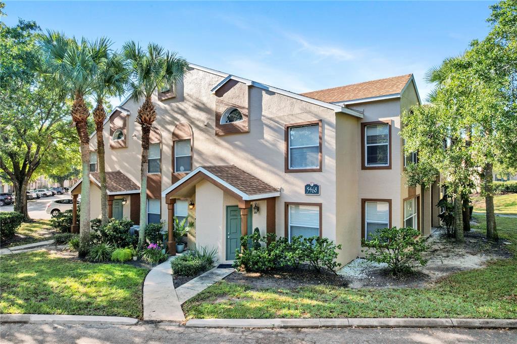 A two-story tan stucco townhouse with a brown shingled roof and palm trees — 5468 E MICHIGAN STREET UNIT 5468-4, ORLANDO, FL