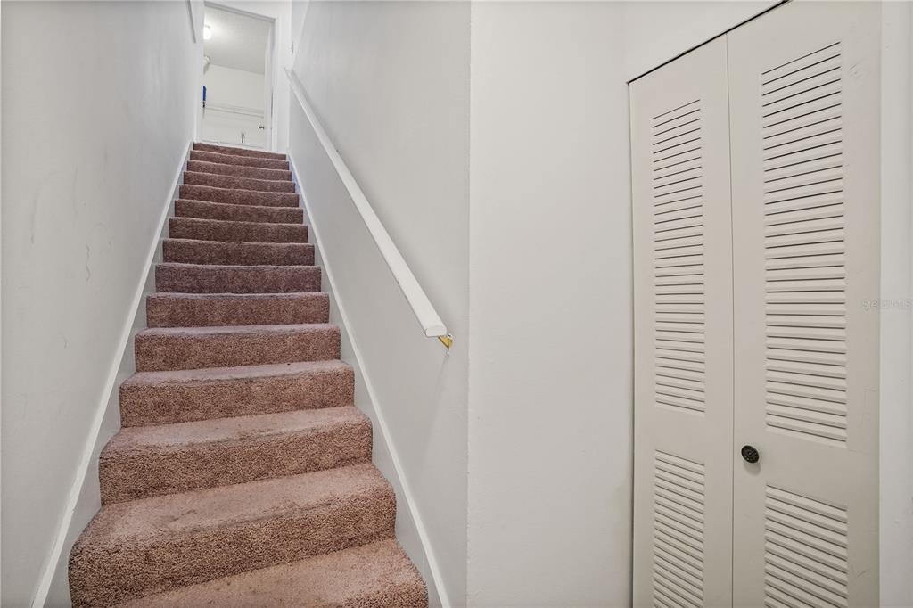 A carpeted staircase leads to an upper landing next to a white louvered closet door — 5468 E MICHIGAN STREET UNIT 5468-4, ORLANDO, FL