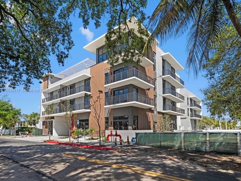 A modern multi-story apartment building with balconies and wood-paneled accents under a clear blue sky — 2479 NE 192nd St # 306, Miami FL 33180, MIAMI, FL