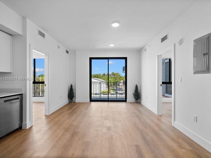 An interior view of a room with light wood floors, white walls, and a balcony door — 2479 NE 192nd St # 306, Miami FL 33180, MIAMI, FL