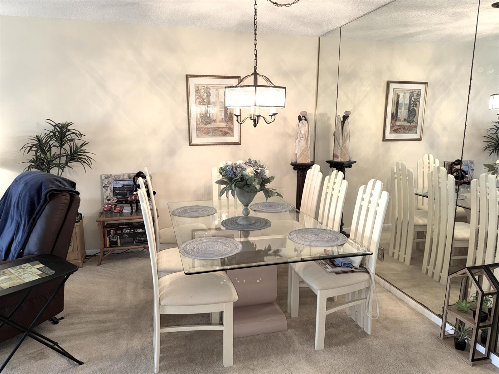 A dining room features a glass-topped table, six white chairs, and a large mirrored wall — 1030 Silk Oak Terrace # 101, Delray Beach FL 33445, DELRAY BEACH, FL