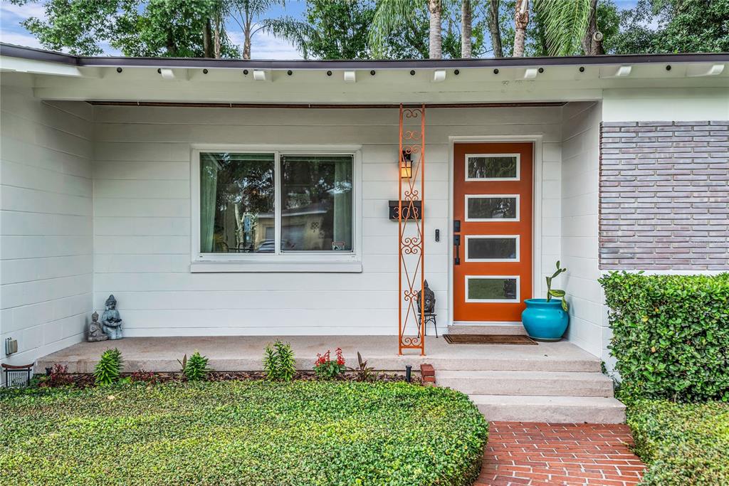 A white house exterior features a bright orange front door and a decorative metal post — 303 E JERSEY STREET, ORLANDO, FL
