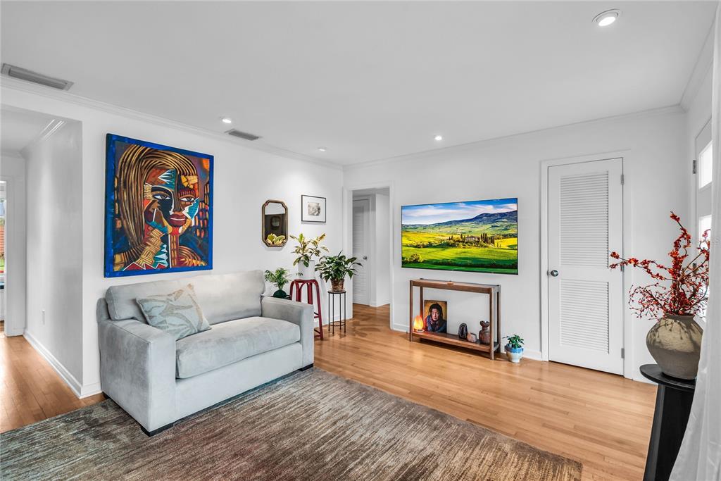 A living room features a grey sofa, a wall-mounted television, and hardwood flooring — 303 E JERSEY STREET, ORLANDO, FL