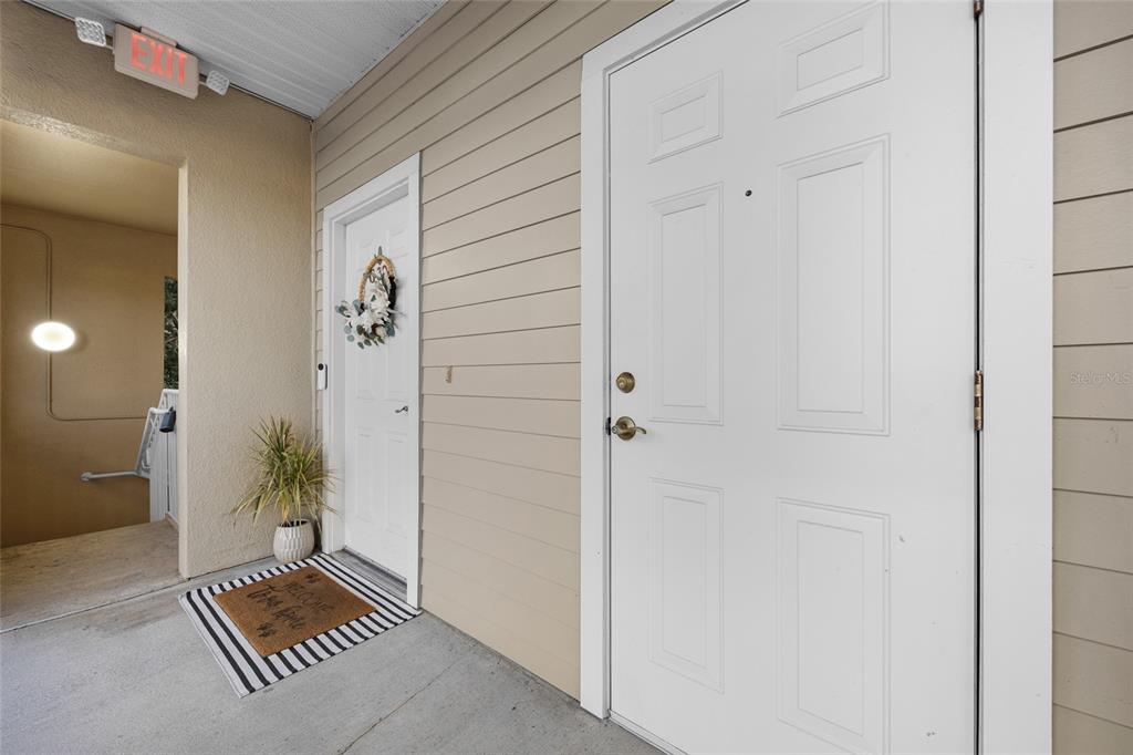 A view of an apartment entryway with two white doors, a welcome mat, and stairs — 5133 SW 91ST CT. COURT UNIT G304, GAINESVILLE, FL