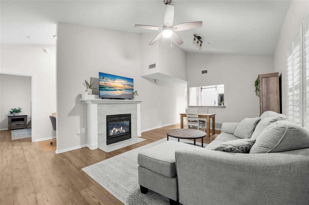A living room features a fireplace with a mounted television, light wood flooring, and furniture — 5133 SW 91ST CT. COURT UNIT G304, GAINESVILLE, FL