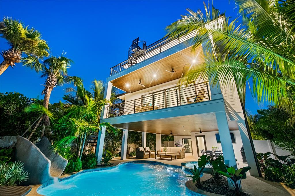 A multi-story house with a swimming pool, a slide, and balconies at dusk — 209 GARFIELD DRIVE, SARASOTA, FL
