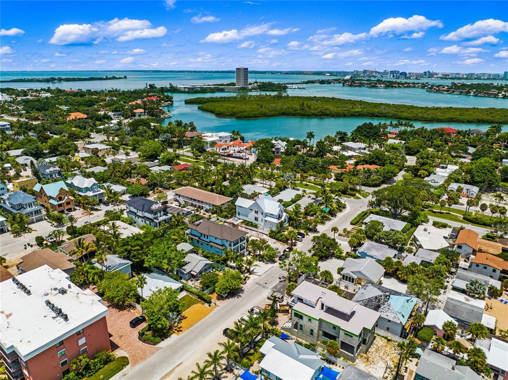 An aerial view shows a coastal neighborhood with houses, lush trees, and a nearby bay — 209 GARFIELD DRIVE, SARASOTA, FL