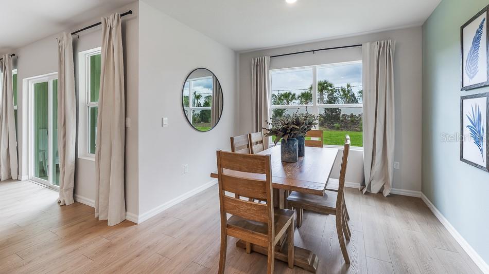 A dining room features a wooden table, chairs, light wood floors, and large windows — 17612 WHISKEY CREEK TRAIL, PARRISH, FL