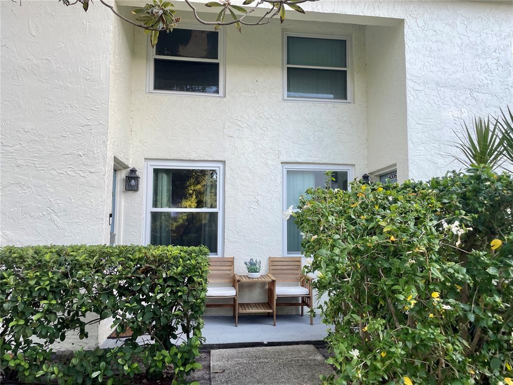 A two-story building exterior features a small patio with two wooden chairs and a table — 4304 LA RIVIERA COURT, TAMPA, FL