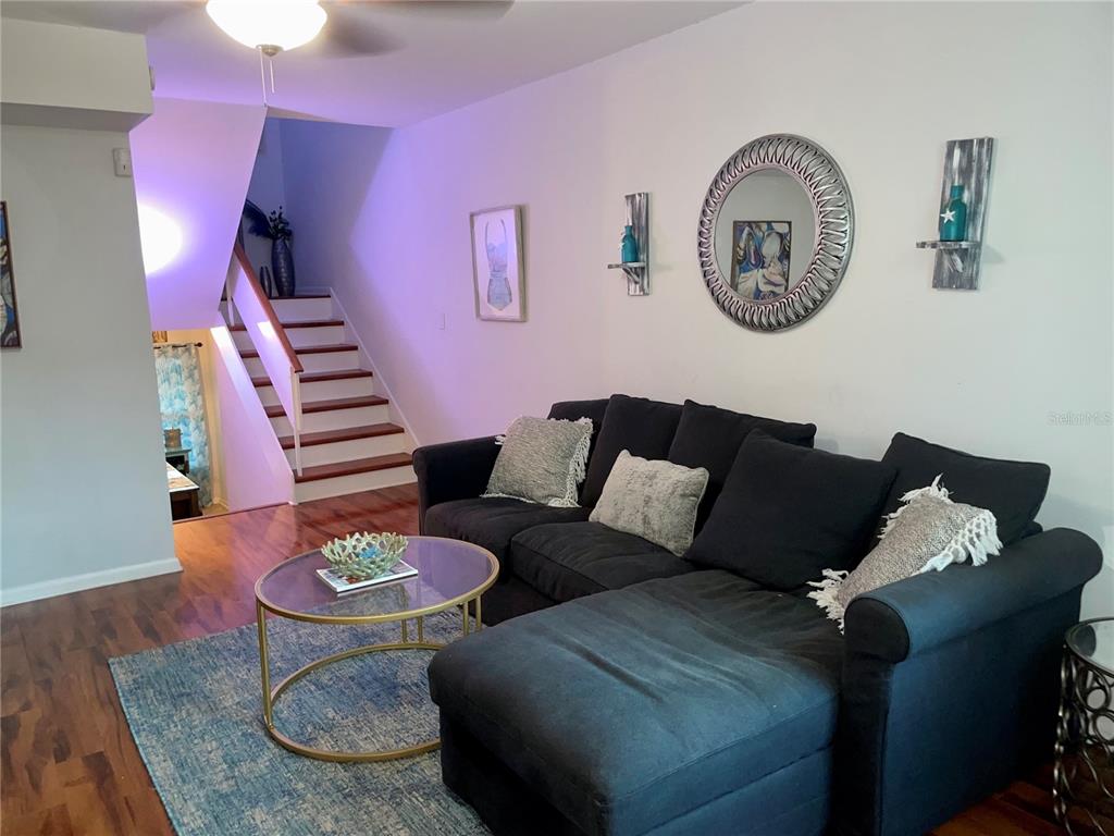 A living room features a dark sectional sofa, a glass coffee table, and a staircase — 4304 LA RIVIERA COURT, TAMPA, FL