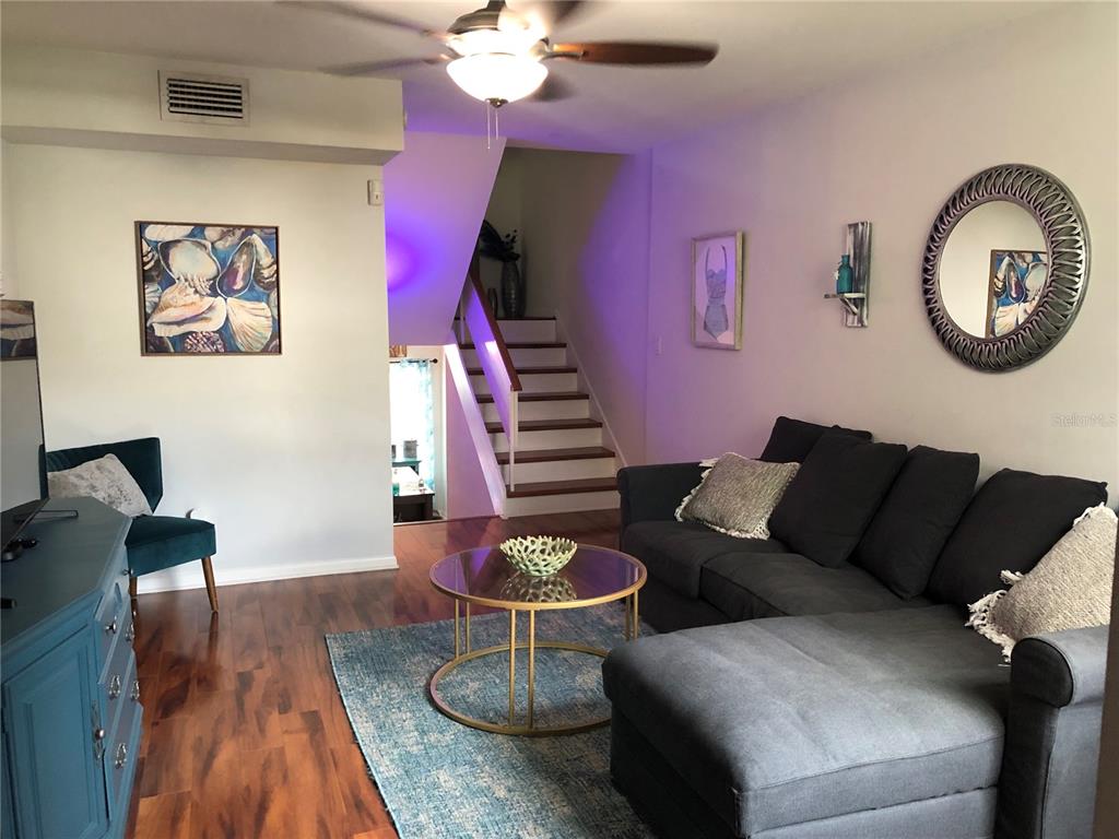 A living room features a dark sectional sofa, a glass coffee table, and a staircase — 4304 LA RIVIERA COURT, TAMPA, FL