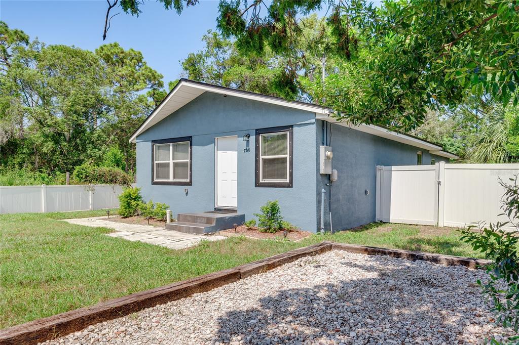 A blue single-story house with a white door and a gravel yard in front — 7515 NEW YORK AVENUE, HUDSON, FL