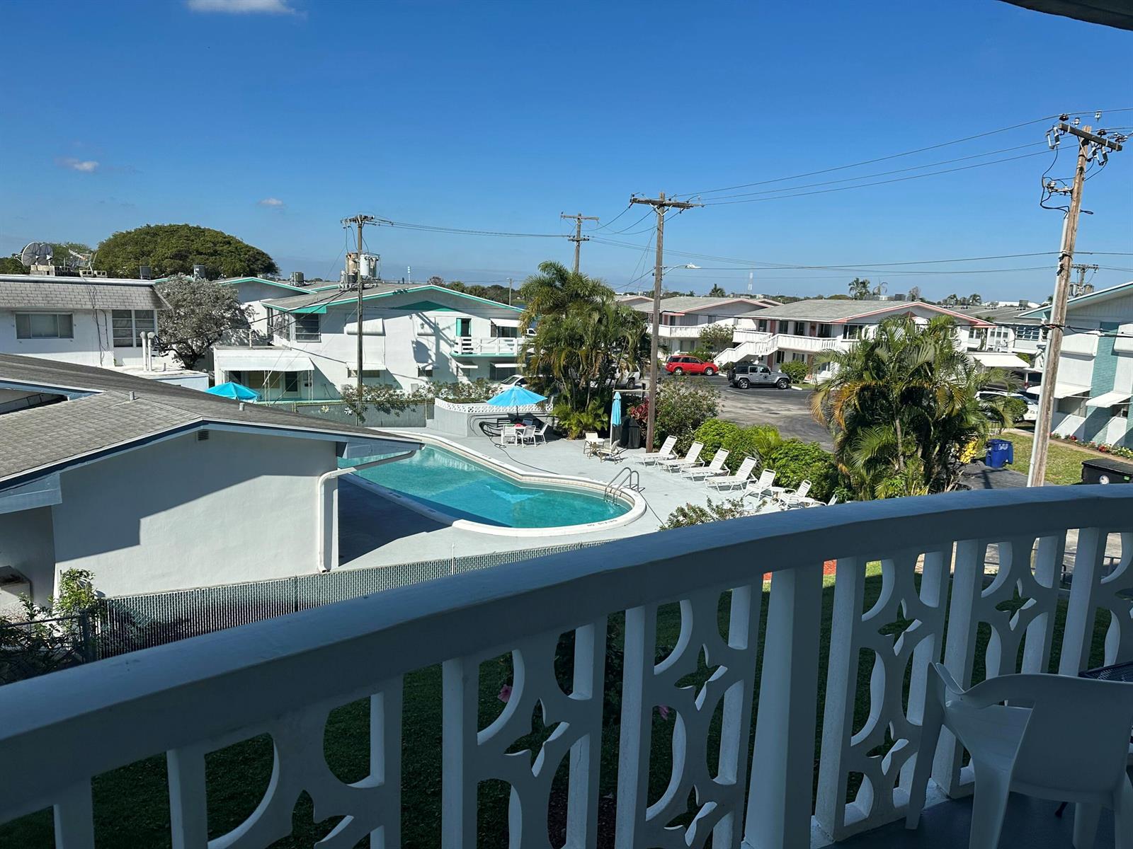 A view from a balcony overlooking a swimming pool and surrounding apartment buildings — 2381 Sunset Avenue # 216, Lake Worth FL 33461, LAKE WORTH, FL