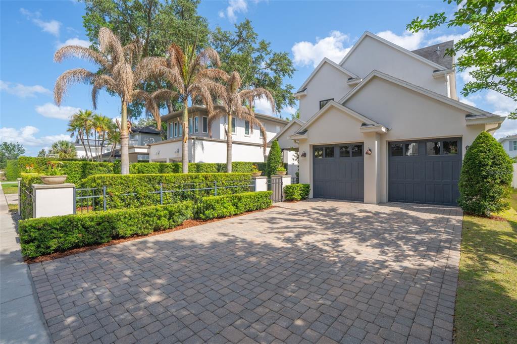 A two-car garage with dark doors faces a paved driveway in front of a house — 1420 MAGNOLIA AVENUE, WINTER PARK, FL