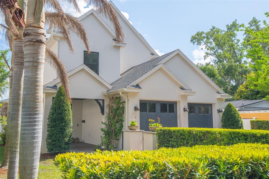 A two-story house with a cream-colored exterior, a two-car garage, and a manicured hedge — 1420 MAGNOLIA AVENUE, WINTER PARK, FL