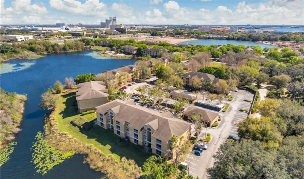 An aerial view shows a multi-story apartment complex situated next to a lake — 7524 SEURAT STREET UNIT 12301, ORLANDO, FL