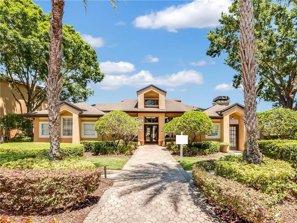 A paved walkway leads to the entrance of a single-story building with tan stucco walls — 7524 SEURAT STREET UNIT 12301, ORLANDO, FL