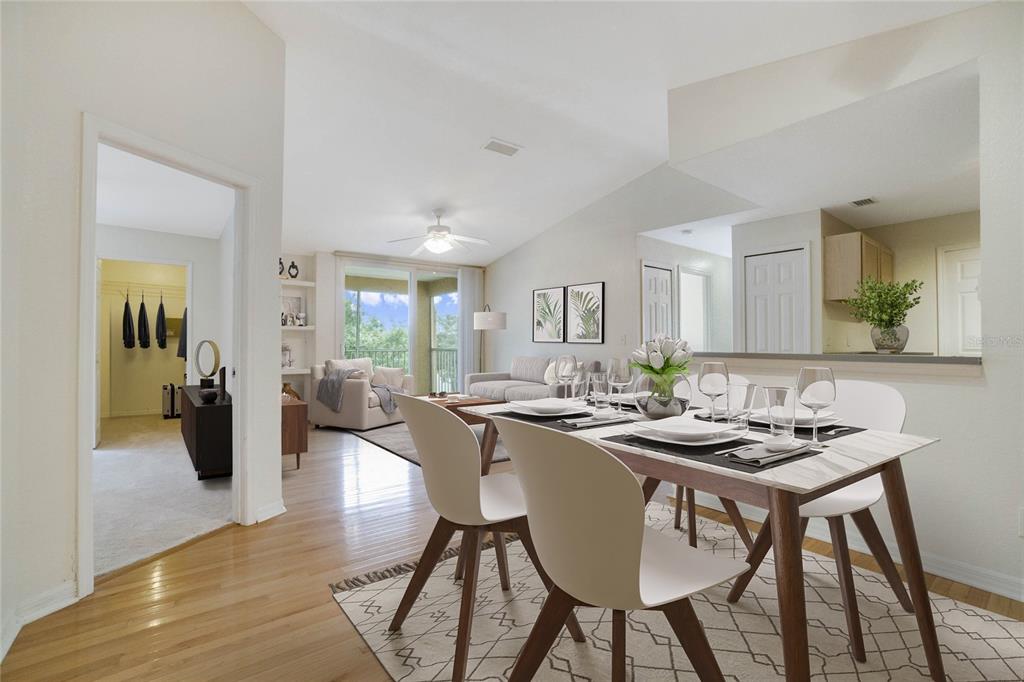 A dining area with a modern table and chairs opens into a bright living room — 7524 SEURAT STREET UNIT 12301, ORLANDO, FL