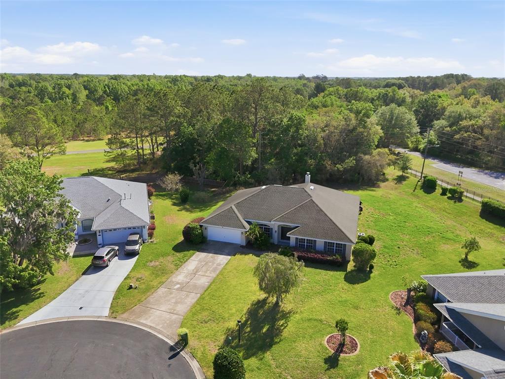 An aerial view shows a suburban house with a driveway and lawn near a forest — 42 SUNRISE DRIVE, OCALA, FL