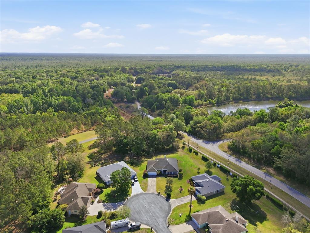 An aerial view shows several suburban houses situated near a forest and a small lake — 42 SUNRISE DRIVE, OCALA, FL