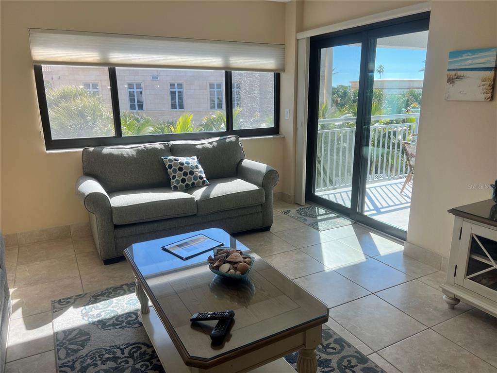 A living room features tile flooring, a gray sofa, a glass-topped coffee table, and balcony access — 1001 POINT OF ROCKS ROAD UNIT 310, SARASOTA, FL