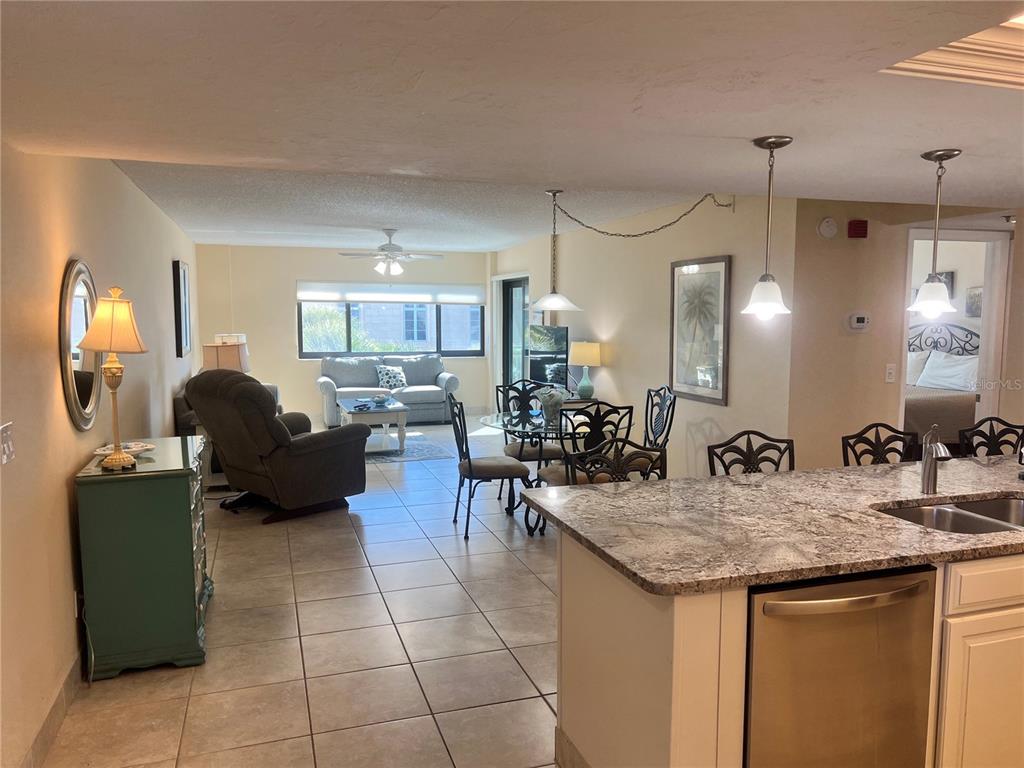 An open-concept living and dining area features tile flooring, a kitchen island, and neutral walls — 1001 POINT OF ROCKS ROAD UNIT 310, SARASOTA, FL